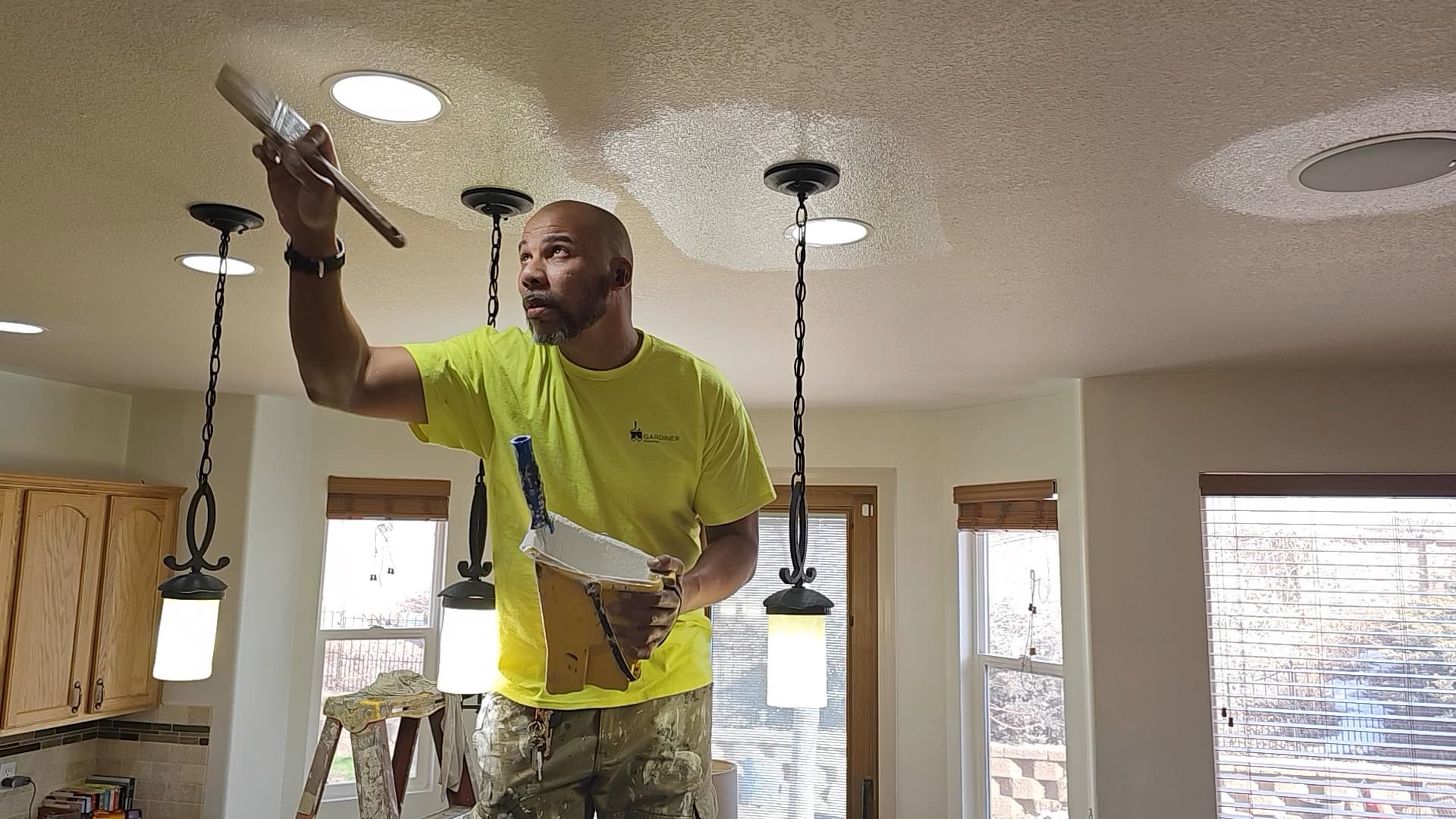 Gardiner worker applying a finish to a textured ceiling inside a home.